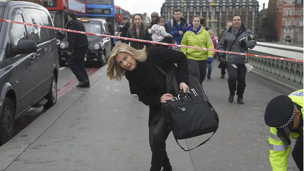 A woman ducks under a police tape after an incident on Westminster Bridge