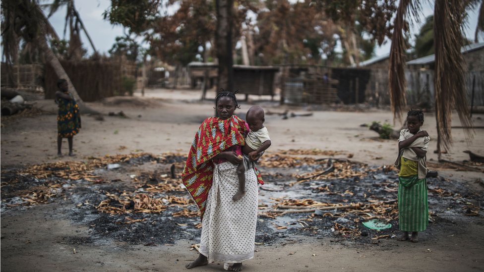 Una mujer sostiene a su hijo menor mientras está parada en un área incendiada cerca de una aldea en la aldea de Aldeia da Paz en las afueras de Macomia, Mozambique - 24 de agosto de 2019