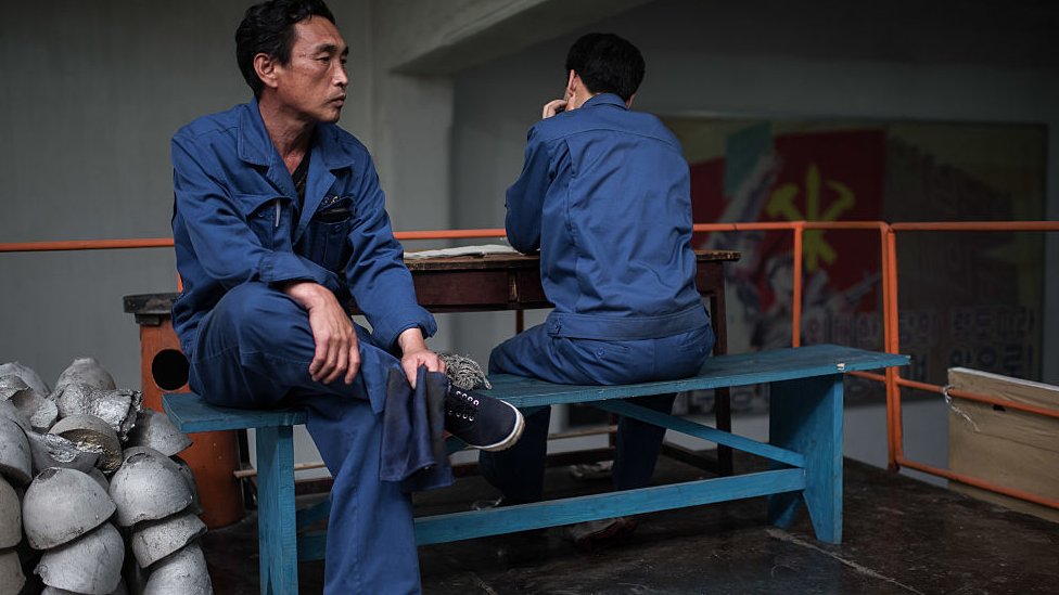 Workers sit on a bench during a media tour of the March 26 Electric Cable Factory in Pyongyang on May 6, 2016