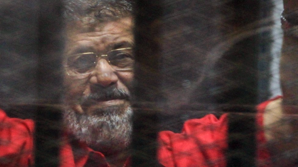 Свергнутый президент Египта Мохамед Морси наблюдает во время судебного заседания по обвинению в шпионаже в Каире,