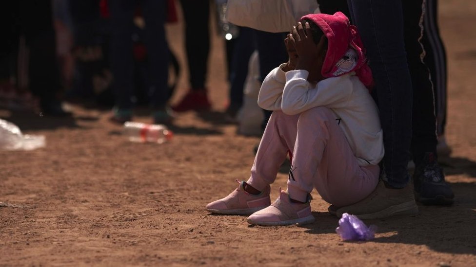 A young black child sits at a migrant camp near the US-Mexico border