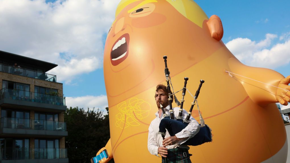 The inflatable Trump Baby with a pipe player in the foreground.