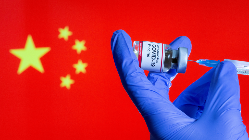 Una vacuna contra el covid frente a una bandera china.
