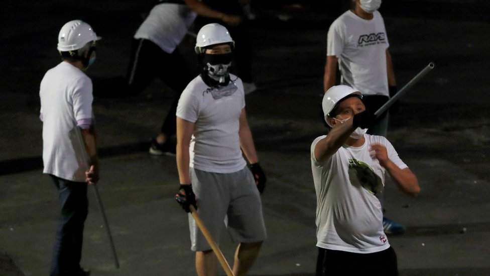 Мужчины в белых футболках с шестами видны в Юэнь Луне после нападения на демонстрантов, выступающих против экстрадиции, на вокзале в Гонконге, Китай, 22 июля 2019 года.