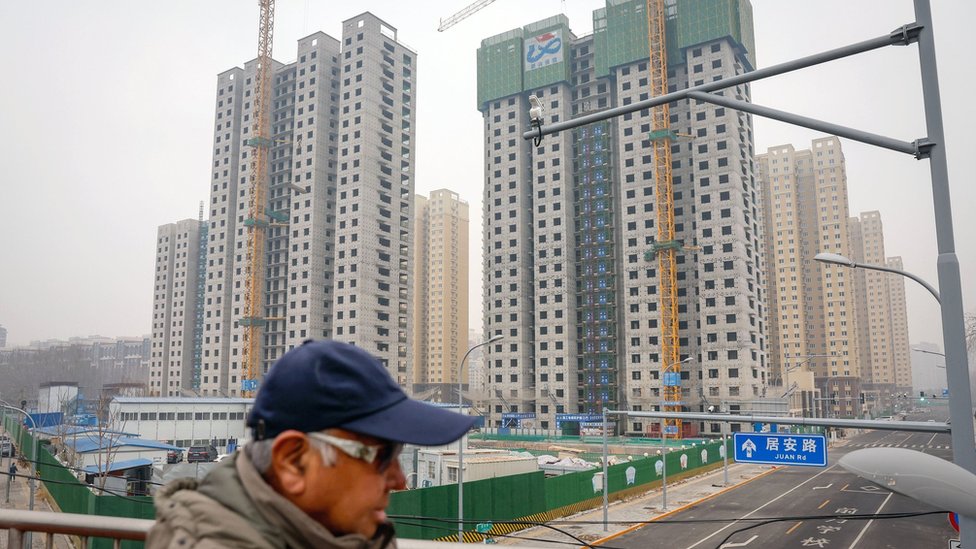 A man walks next to the construction site of a residential building in Beijing, China, 17 January 2024