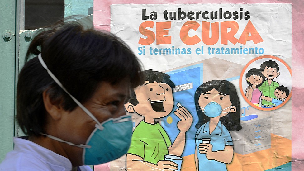 Una persona en Perú pasa frente a un cartel que dice "la tuberculosis se cura".