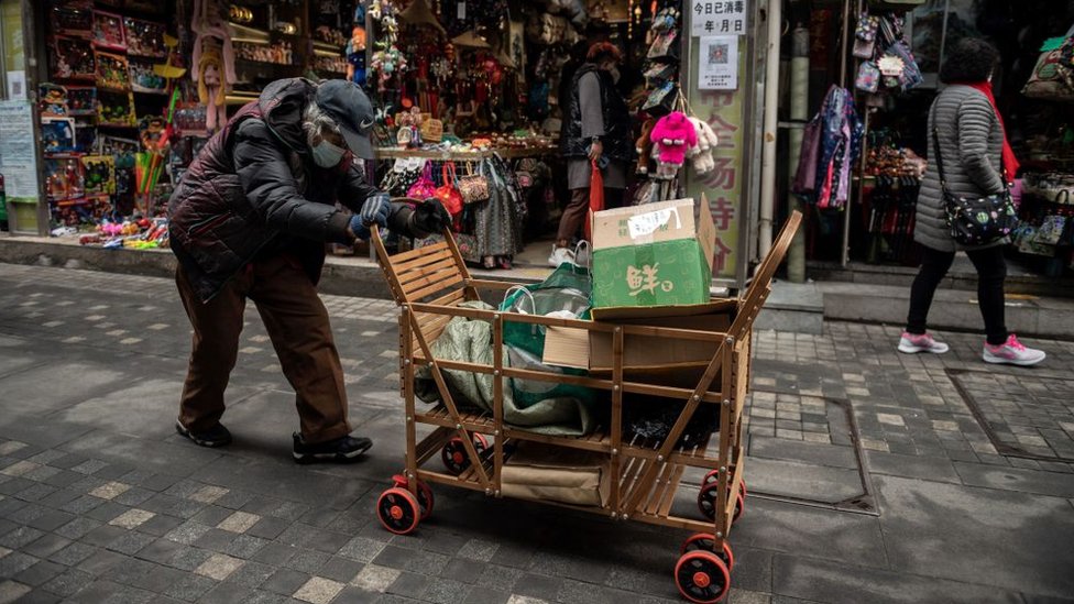 An elderly woman pushes a cart after searching through rubbish bins to collect recyclable items to sell, along a street near the Great Hall of the People in Beijing.
