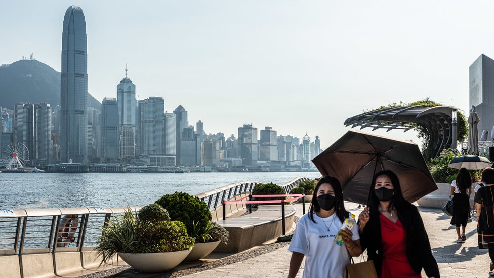 香港尖沙咀海旁兩位戴著口罩的女士撐著雨傘遮擋陽光（24/7/2022）