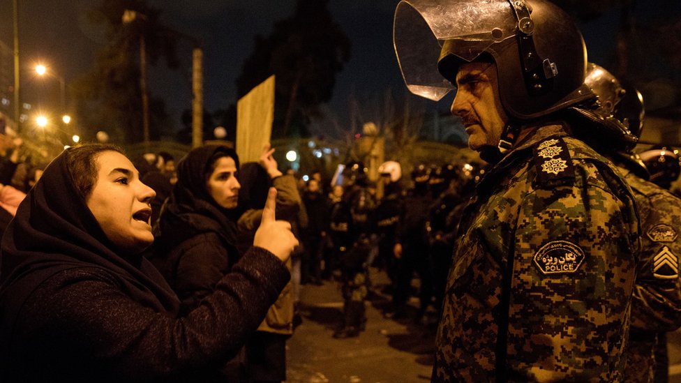 Женщина разговаривает с полицейским на собрании перед университетом Амиркабир в Тегеране