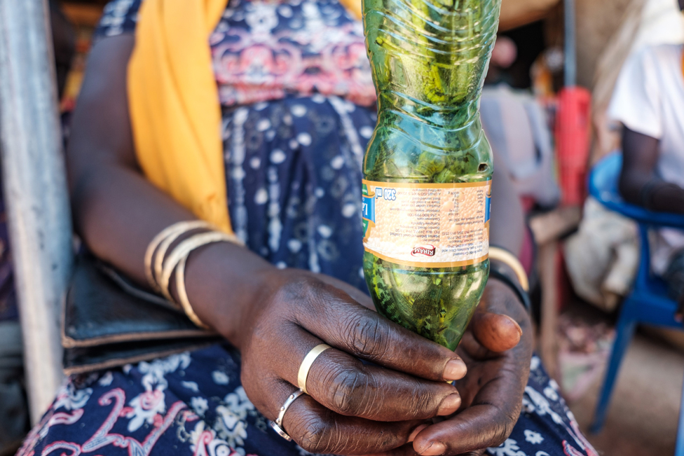 Женщина держит пластиковую бутылку, наполненную саранчой