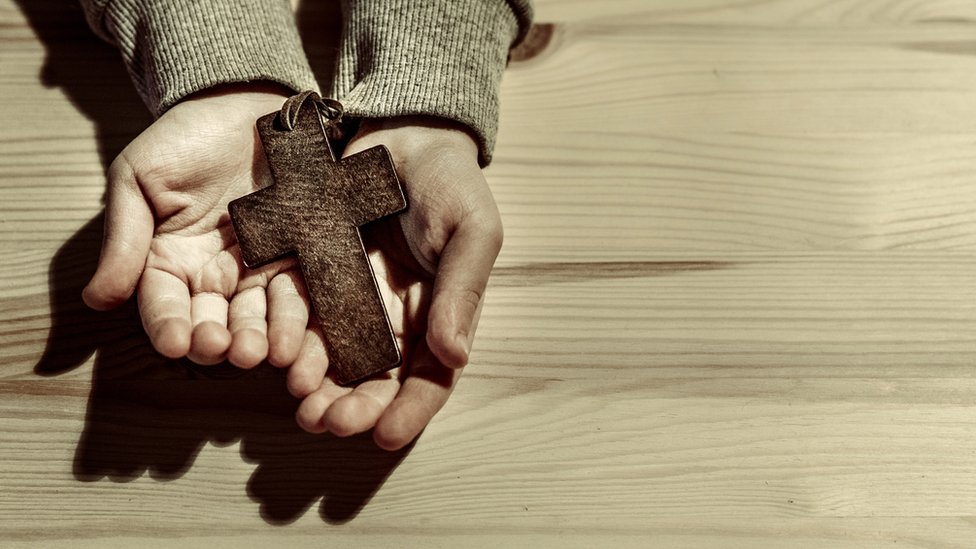 Muchos movimientos de ideología conservadora defienden la defensa de la religión cristiana. Mano de varón con una cruz.