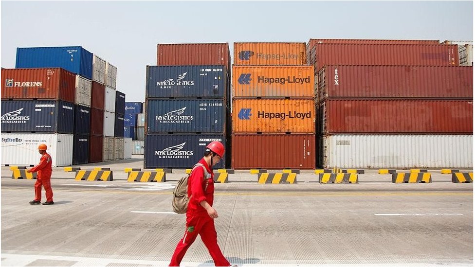 A worker walks past stacked containers at the Yangshan Deepwater Container Port in Shanghai, China on 02 June 2011.