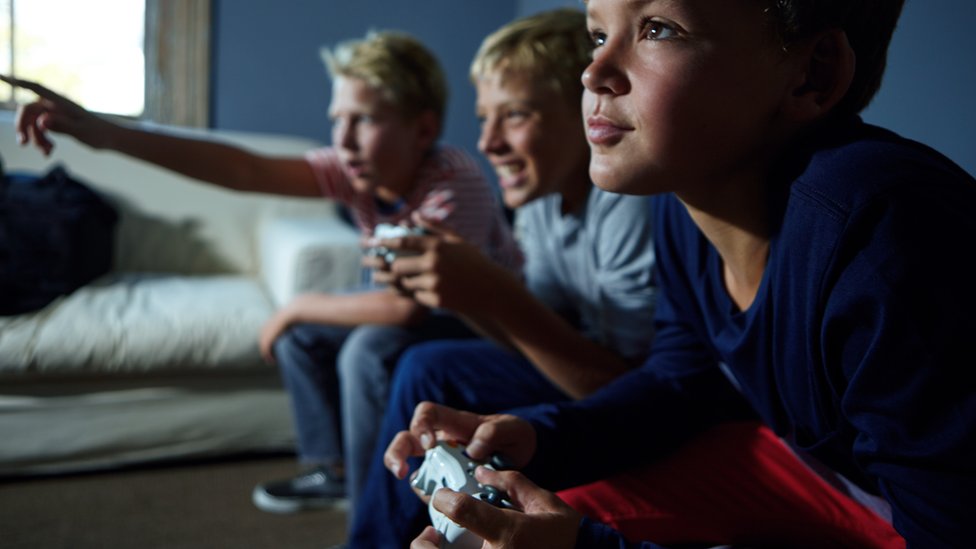 tres niños jugando videojuegos.