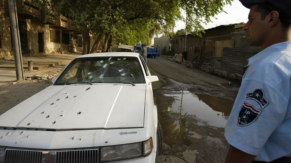 Иракский полицейский стоит у изрешеченной пулями машины двух женщин, предположительно застреленных частными охранниками в центре Багдада, 9 октября 2007 г.
