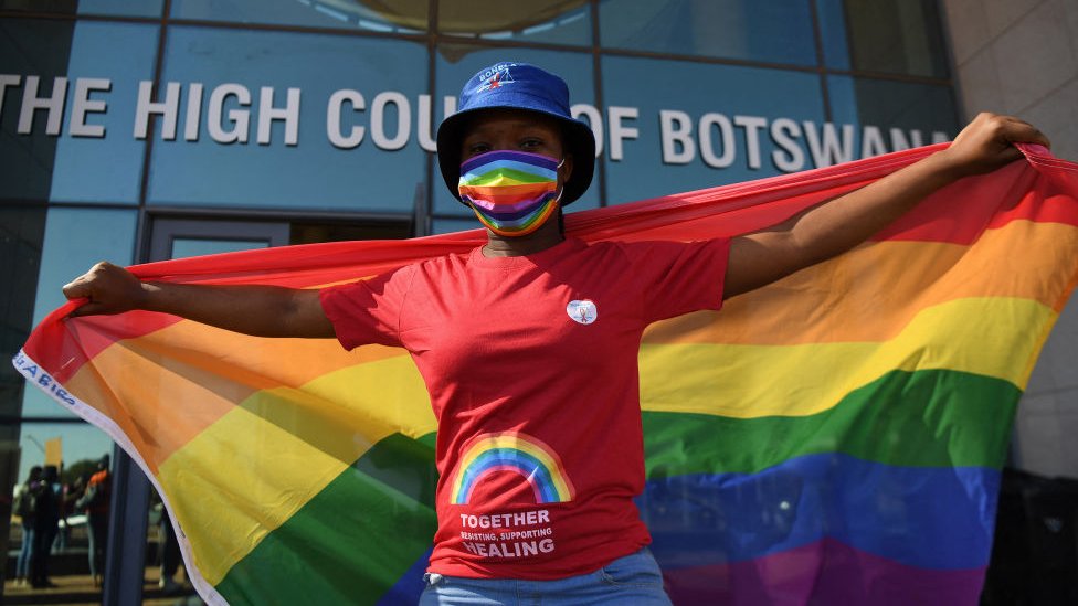 Mujer con la bandera arcoiris frente a un tribunal de Botswana.