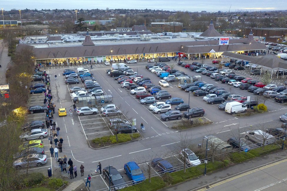 A large supermarket with a very long queue winding around the car park