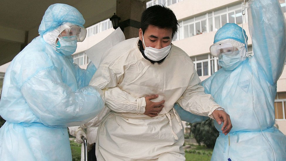 Paciente siendo aislado por personal médico en China en 2003.