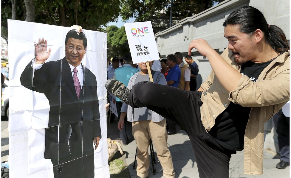 Активист пинает портрет президента Китая Си Цзиньпина во время акции протеста против предстоящей встречи президента Тайваня Ма Ин-цзю и президента Китая Си Цзиньпина перед зданием президента в Тайбэе, Тайвань, 5 ноября 2015 года.