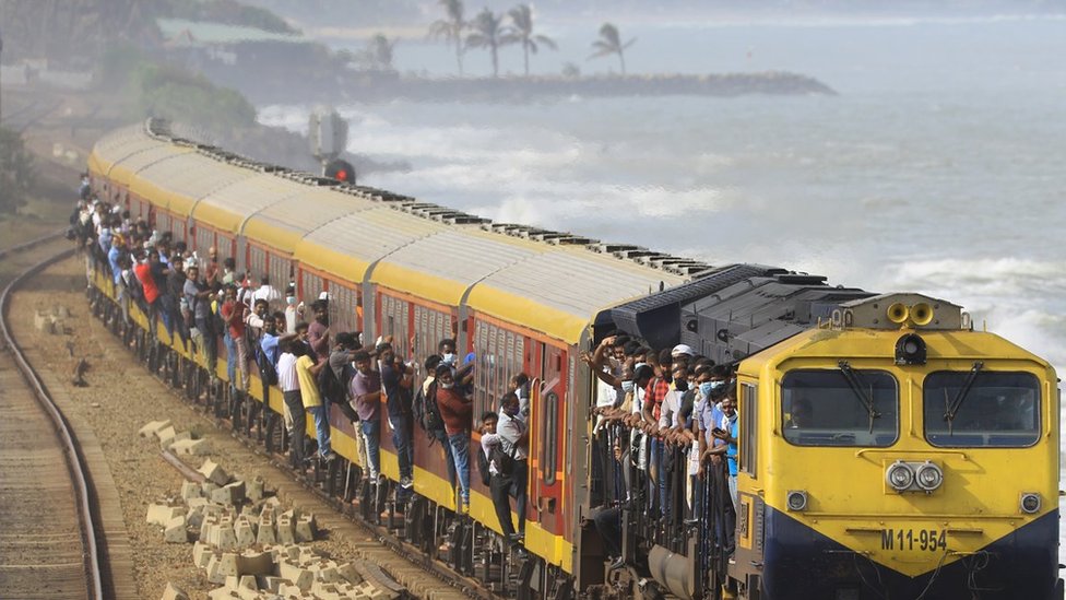 Sri Lankan commuters hang on to the over-crowded train as it arrives at Colombo, Sri Lanka. 6 July 2022.
