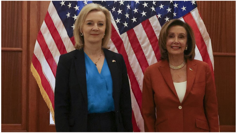 Liz Truss and Nancy Pelosi stand shoulder to shoulder in front of the USA flag