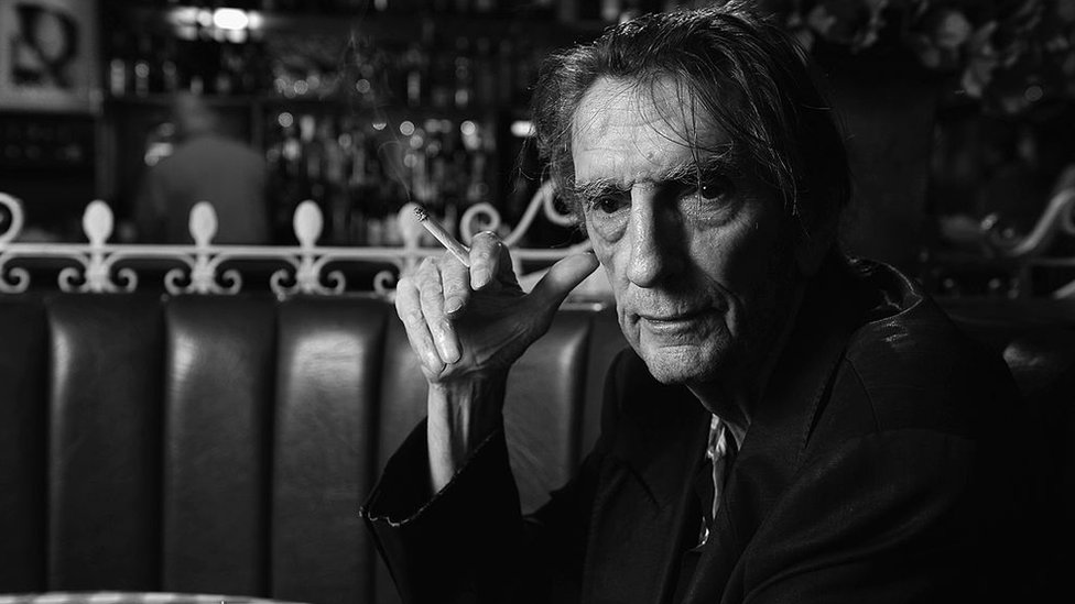 Stanton murió de causas naturales en un hospital de Los Ángeles. stanton fumando en un café