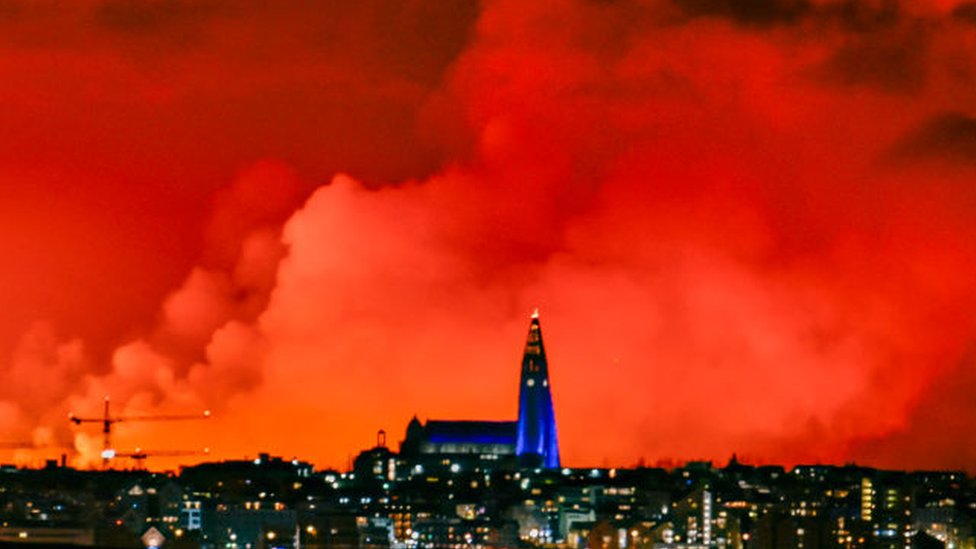 The skyline of Reykjavik turns orange from the lava flowing from a fissure caused by a volcanic eruption
