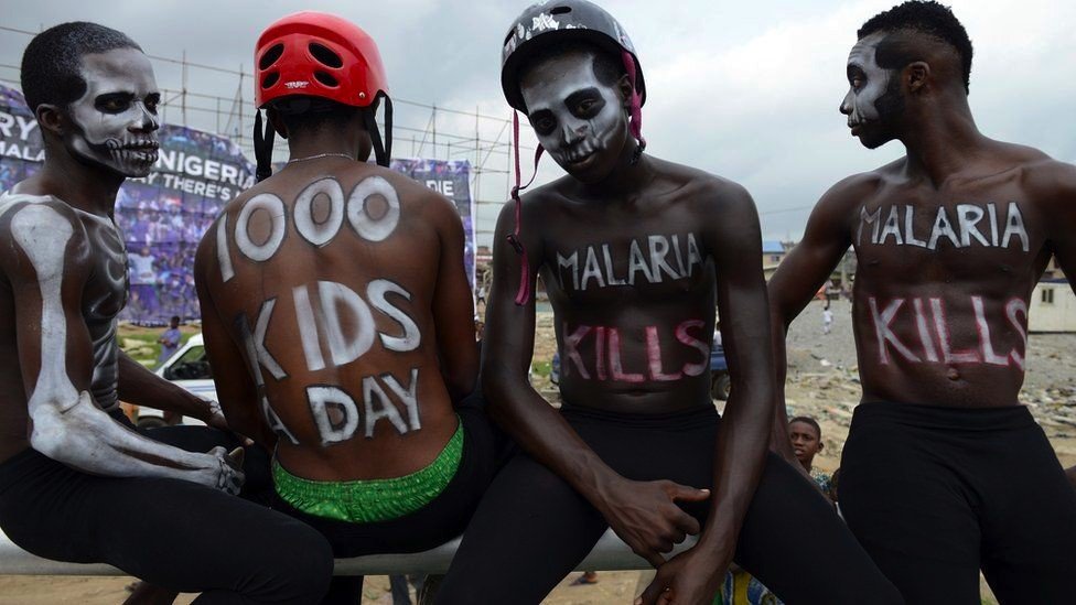 Four men with slogans painted on them take part in an anti-malaria campaign