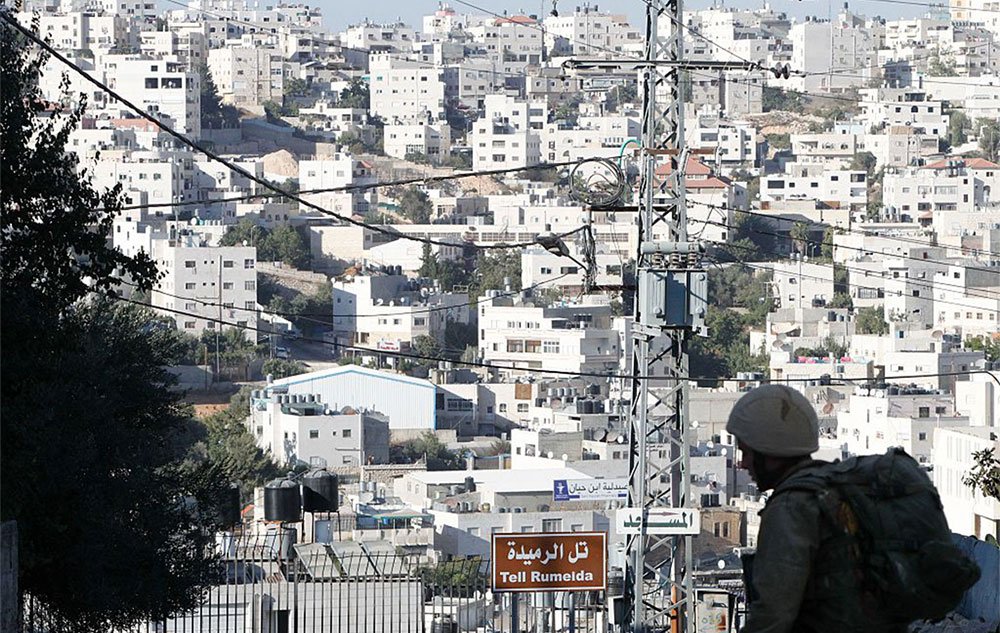 الصراع الفلسطيني الإٍسرائيلي: هوة واسعة بين آمال السلام وواقعه 2 An Israeli soldier stands guard at the entrance to a Jewish settlers zone in Hebron, 2016