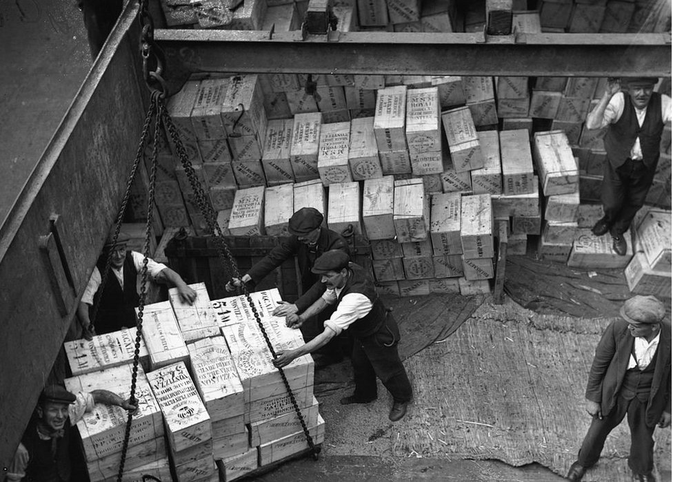 Рабочие выгружают партию сухофруктов из трюма корабля в лондонских доках в 1930 году