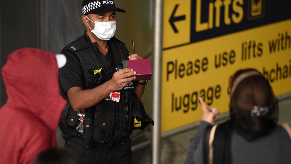 Офицер полиции разговаривает с пассажирами в аэропорту Манчестера
