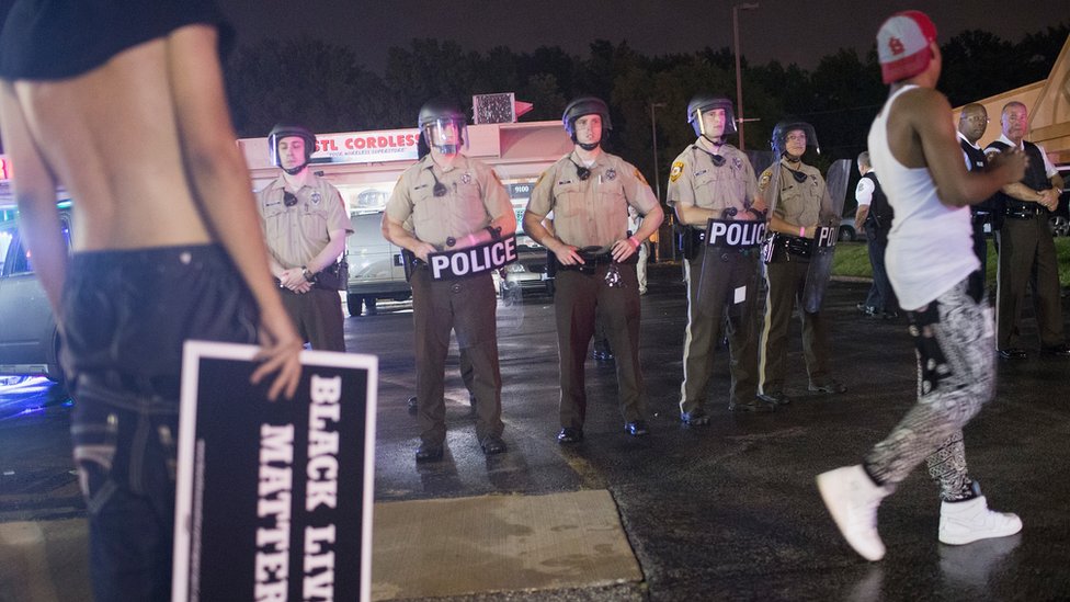 Очередь полицейских стоит за протестующими в Фергюсоне, штат Миссури