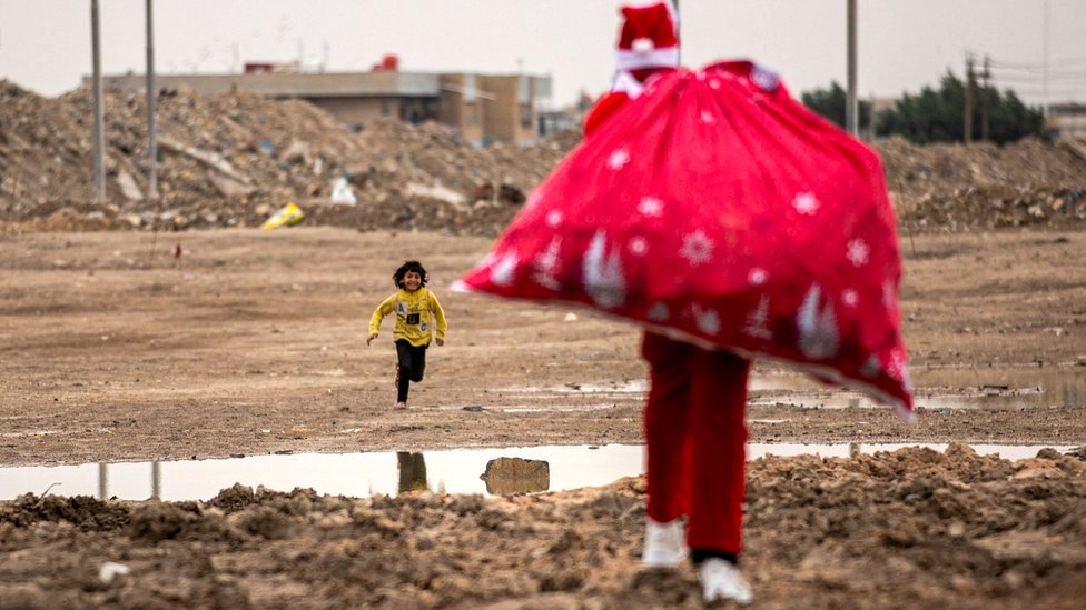 伊拉克南部城市巴斯拉貧民區，聖誕老人迎向奔跑而來的小童