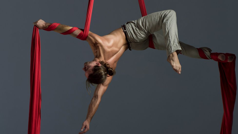 Persona haciendo ejercicio con una tela acrobática.