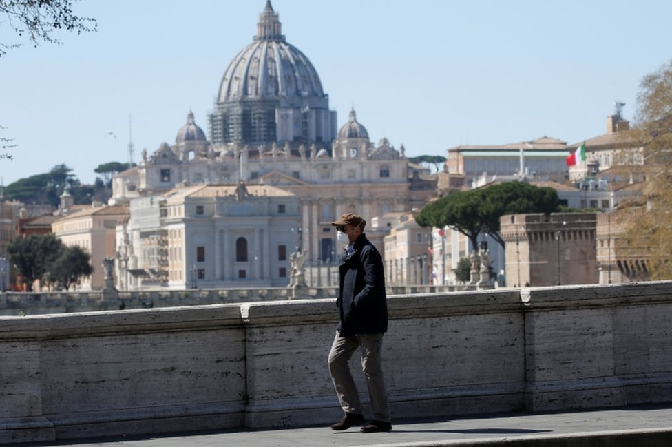 Мужчина в маске проходит мимо базилики Святого Петра