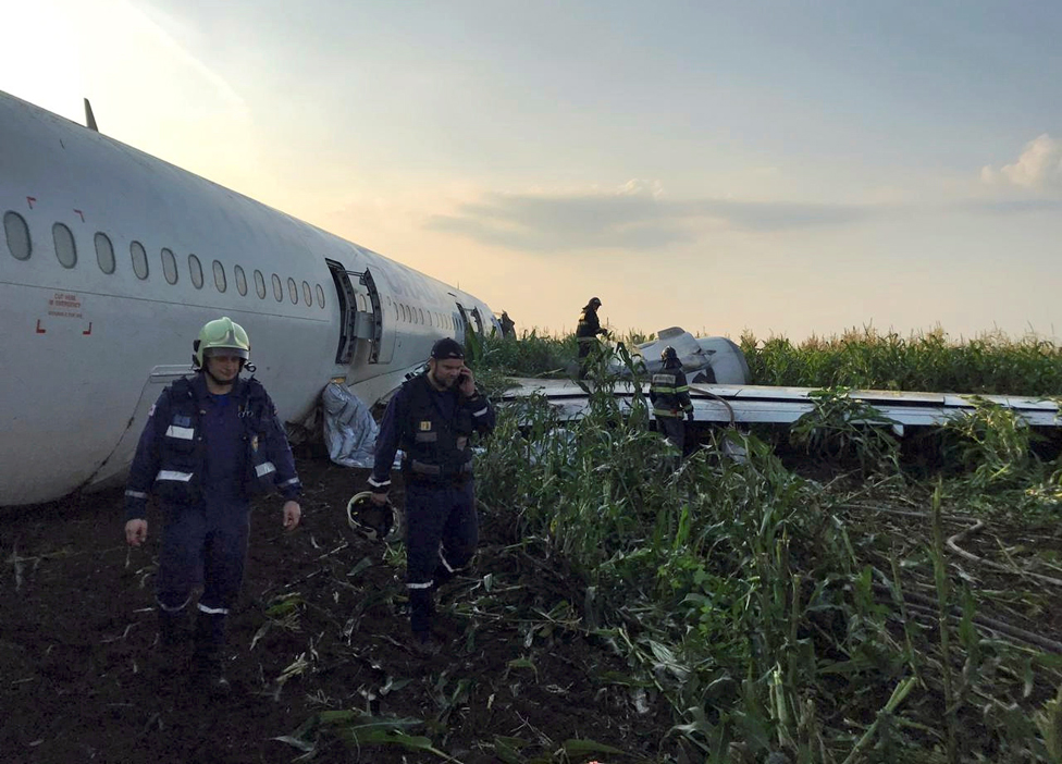 Спасатели обслуживают самолет Airbus 321 "Уральских авиалиний" после аварийной посадки возле международного аэропорта Жуковский в Московской области.
