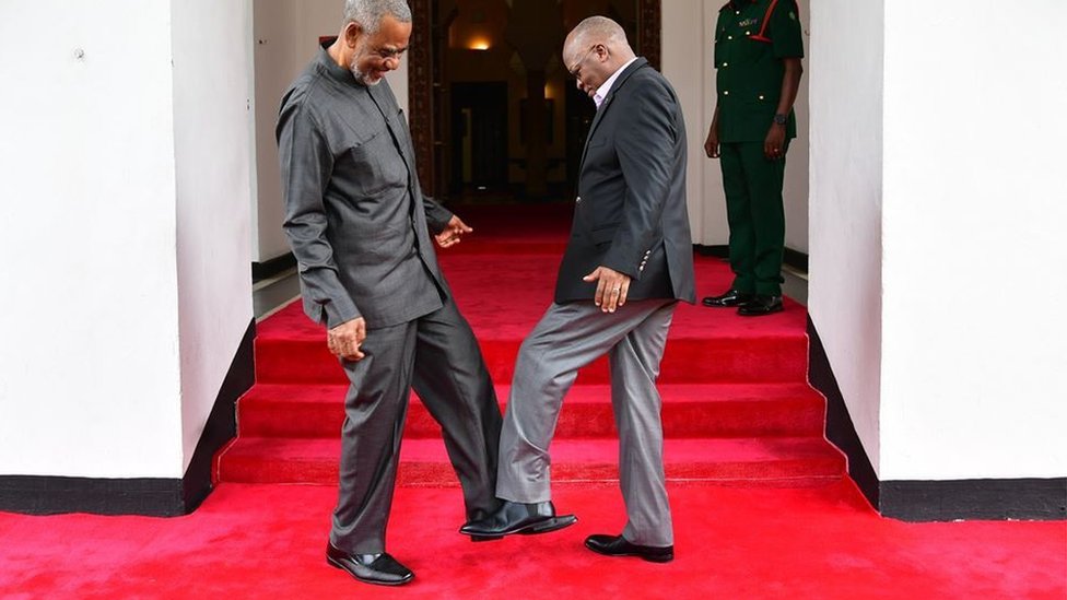 Президент Танзании Джон Магуфули (справа) приветствует танзанийского оппозиционного политика Маалима Сеифа Шарифа Хамада (слева), стуча ногами по их ногам, чтобы избежать коронавируса в Занзибаре, Танзания, 3 марта 2020 г.