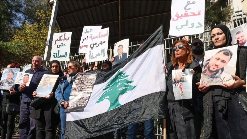 أقارب ضحايا انفجار مرفأ بيروت يحملون صورهم