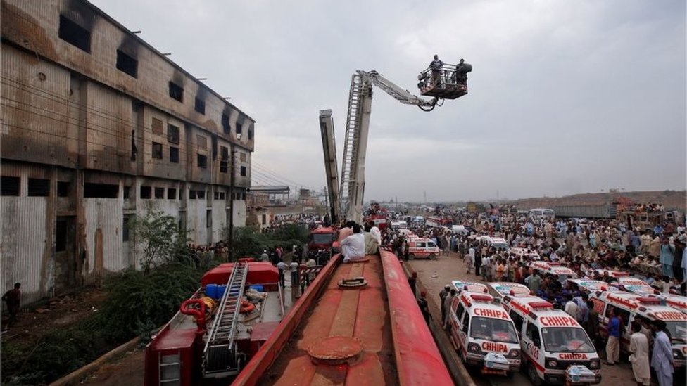 Машины скорой помощи и пожарные машины возле здания после пожара на швейной фабрике в Карачи 12 сентября 2012 г.