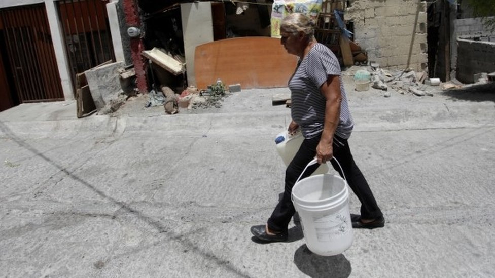 Una mujer carga bidones de agua