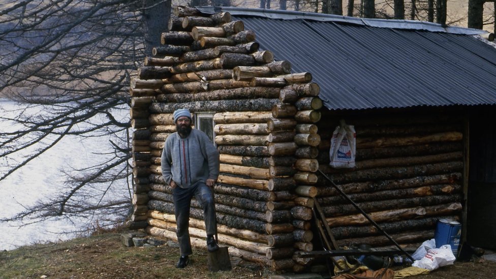 Ken junto a su cabaña de troncos, poco después de que terminó de construirla a mediados de la década de 1980.