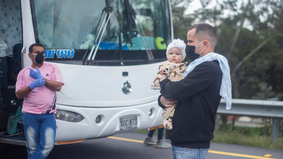 Venezolano con bebé se preparar a abordar un bus de regreso a Venezuela