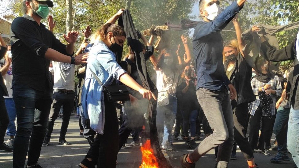 Homens e mulheres jovens dançam durante um protesto nas ruas de Teerã em 1º de outubro