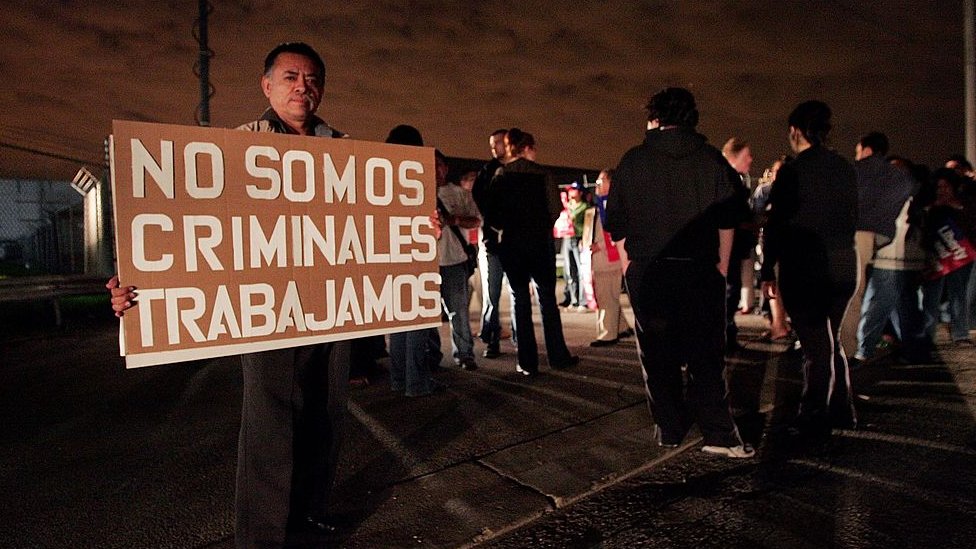 Un hombre sostiene un cartel que dice "No somos criminales, trabajamos"