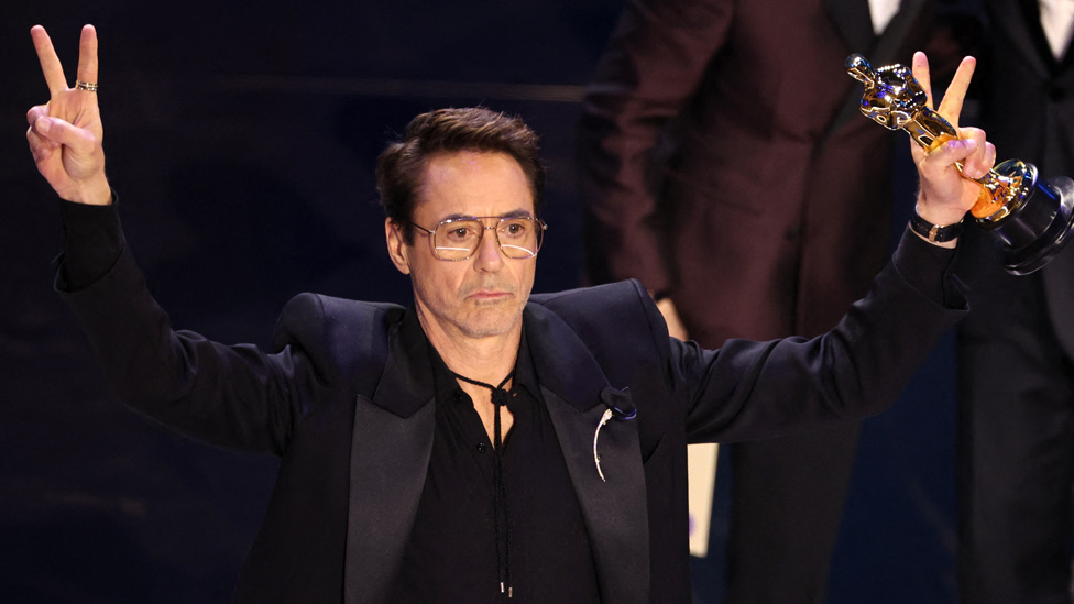 Robert Downey Jr holding up his Oscars