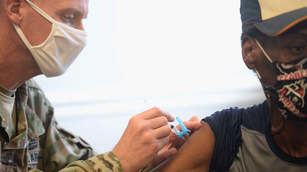 Un hombre inocula una vacuna a otro