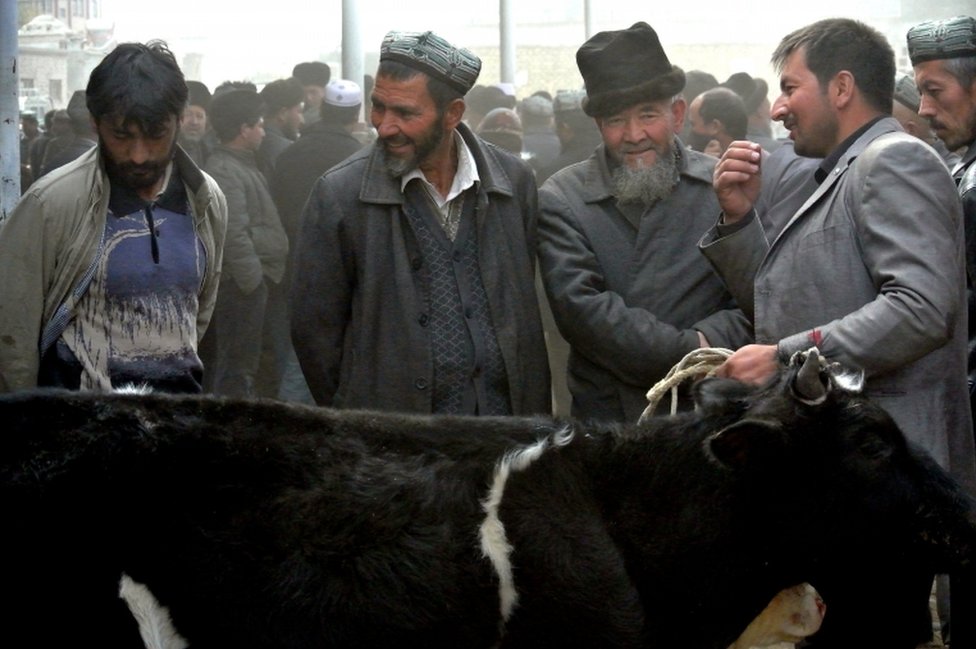 Uighur men gather at a bazaar to sell their sheep in Hotan, in the Xinjiang region