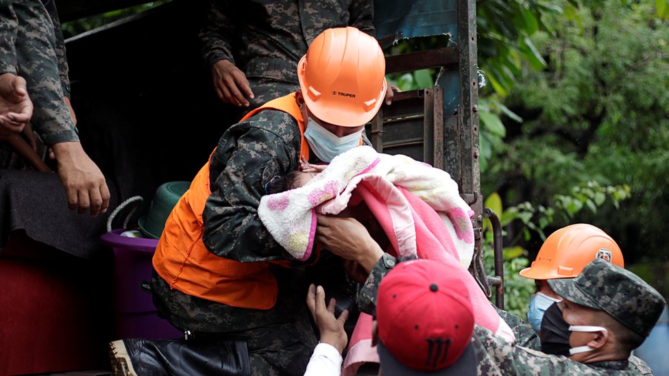 Miembros del ejército suben un bebé a un camión en Honduras