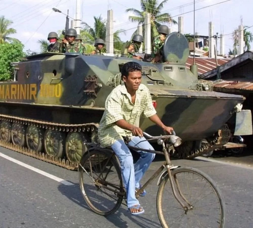 Seorang warga Kota Bireun, Aceh, mengendarai sepeda di samping tank TNI, 26 Mei 2003, saat wilayah itu dilanda konflik bersenjata.