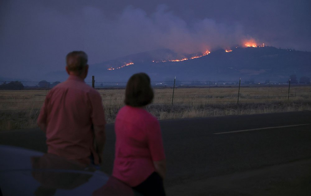 Local residents look at smoke and fire over a hill during wildfires near the town of Medford, Oregon, 9 September 2020
