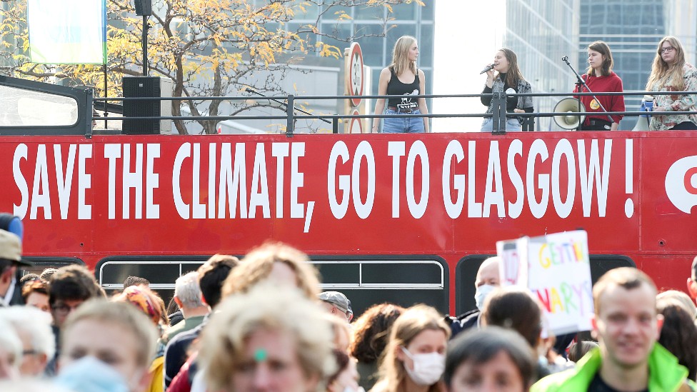 Jóvenes en un autobús con un cartel que dice "salvar el clima, ir a Glasgow"